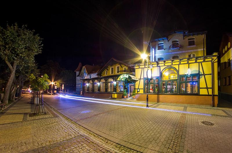 a city street at night with a yellow building at Hotel Alga in Ustka