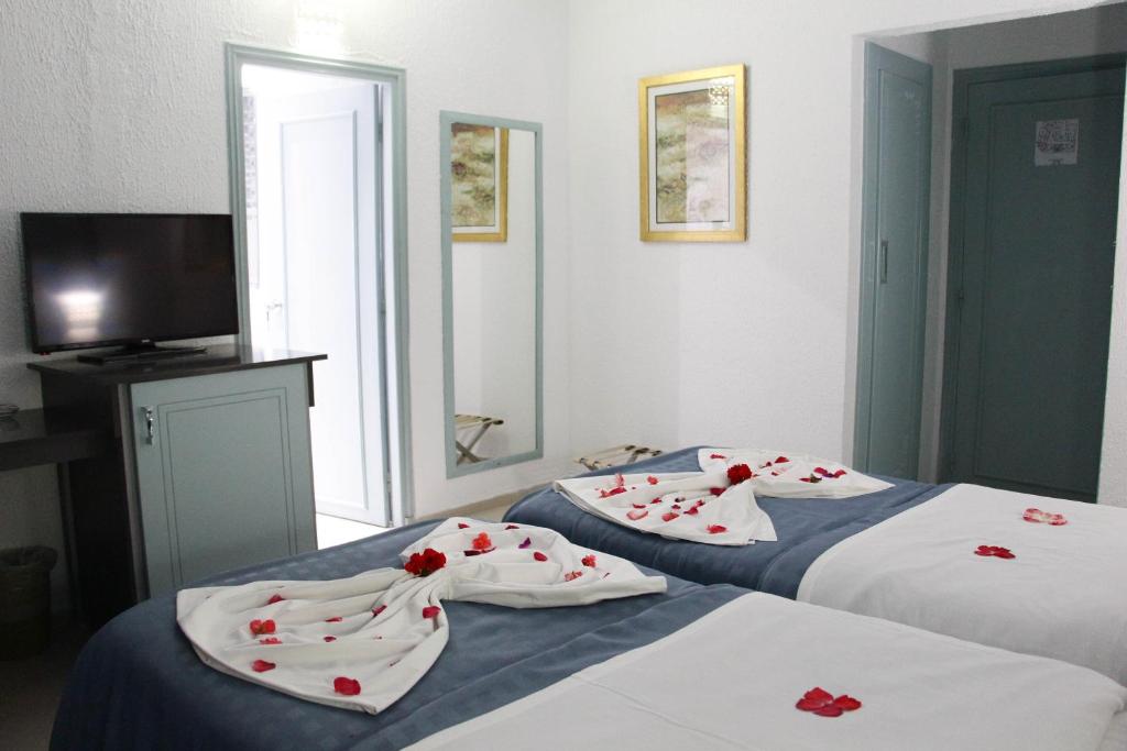 two beds in a room with red flowers on them at Hotel Khella in Hammamet