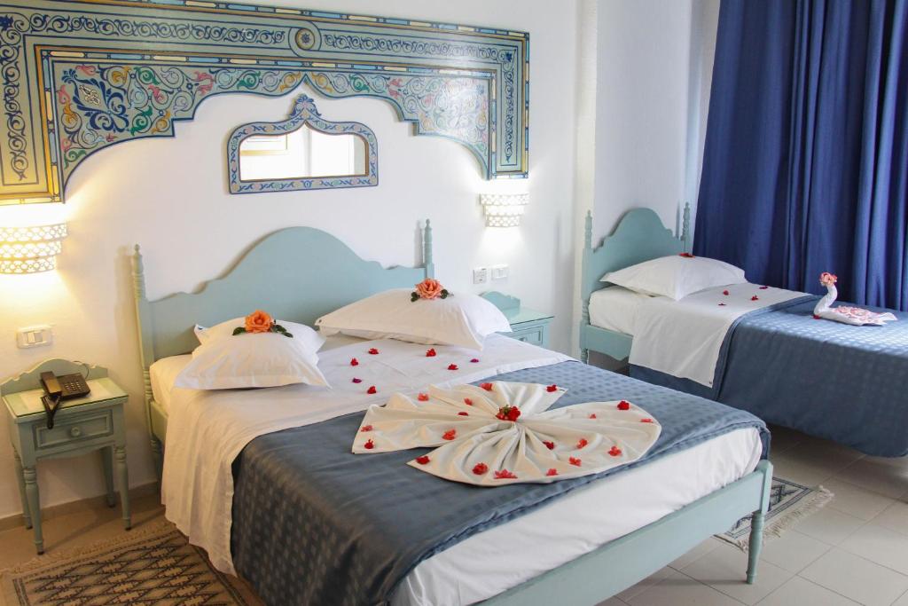 a bedroom with two beds with flowers on them at Hotel Khella in Hammamet
