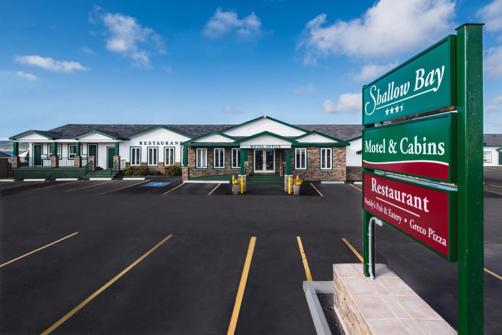 Shallow Bay Motel & Cabins Conference Centre في Cow Head: علامة في موقف للسيارات أمام المبنى