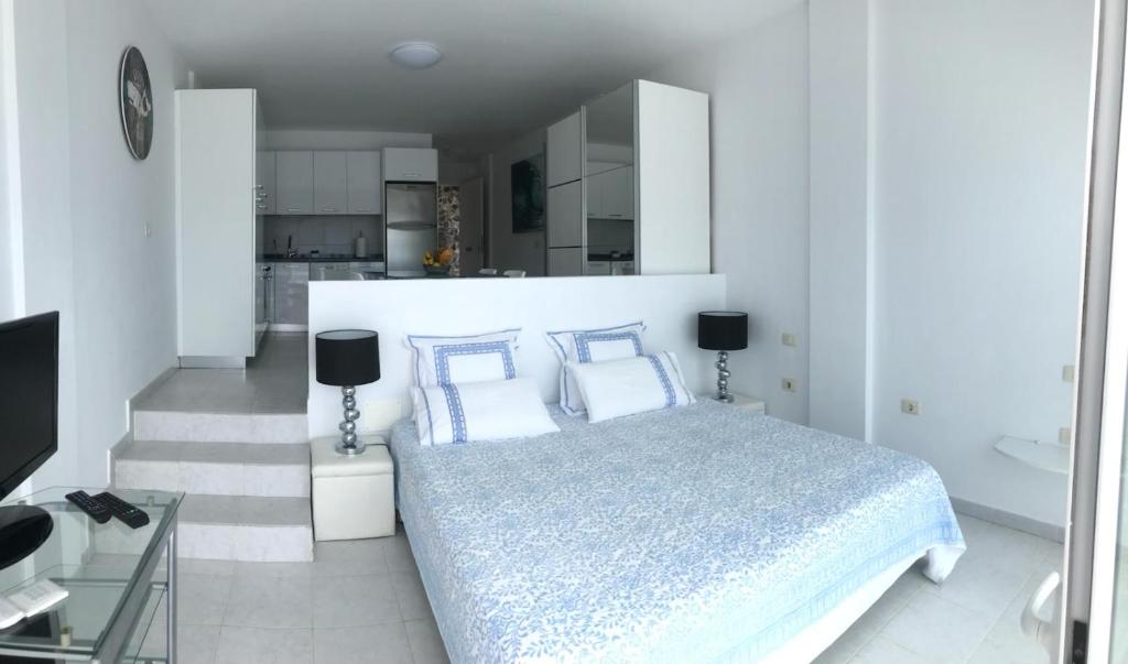 カジャオ・サルバヘにあるLas Barandasの白いベッドルーム(ベッド1台付)、キッチンが備わります。