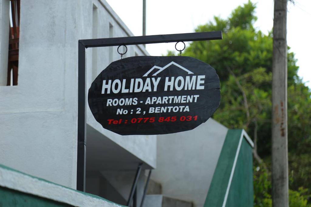 a sign for a holiday home on the side of a building at Holiday Home Bentota in Bentota