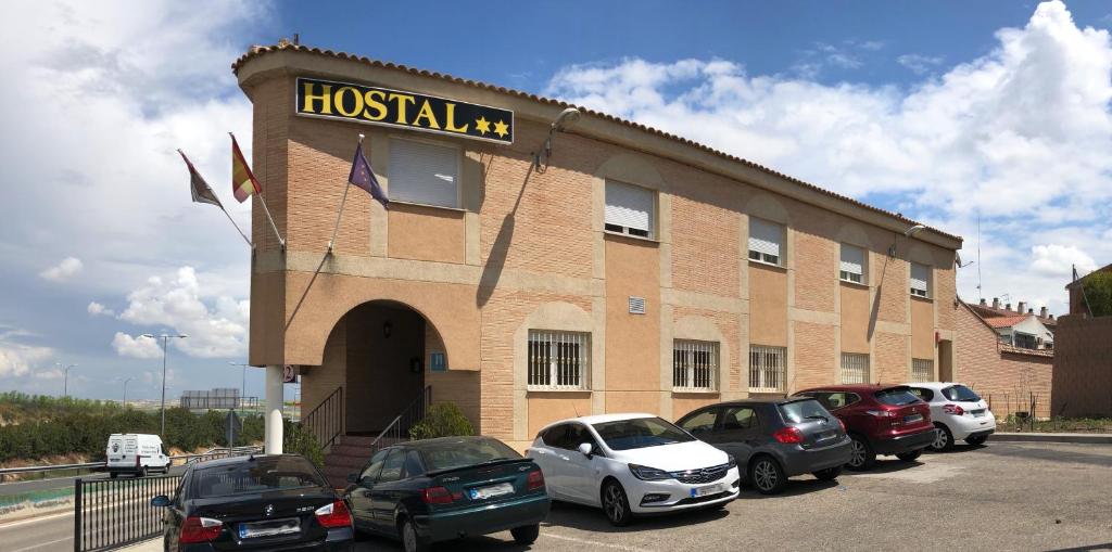 a building with cars parked in a parking lot at Hostal 82 in Olías del Rey