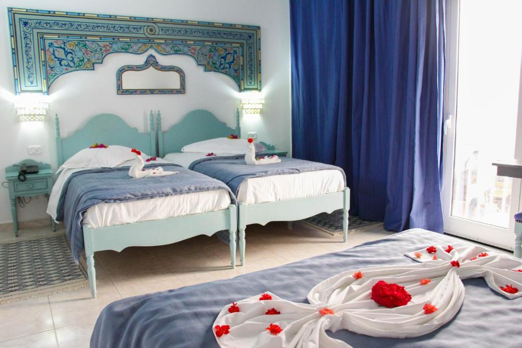 a bedroom with two beds with roses on them at Hotel Khella in Hammamet
