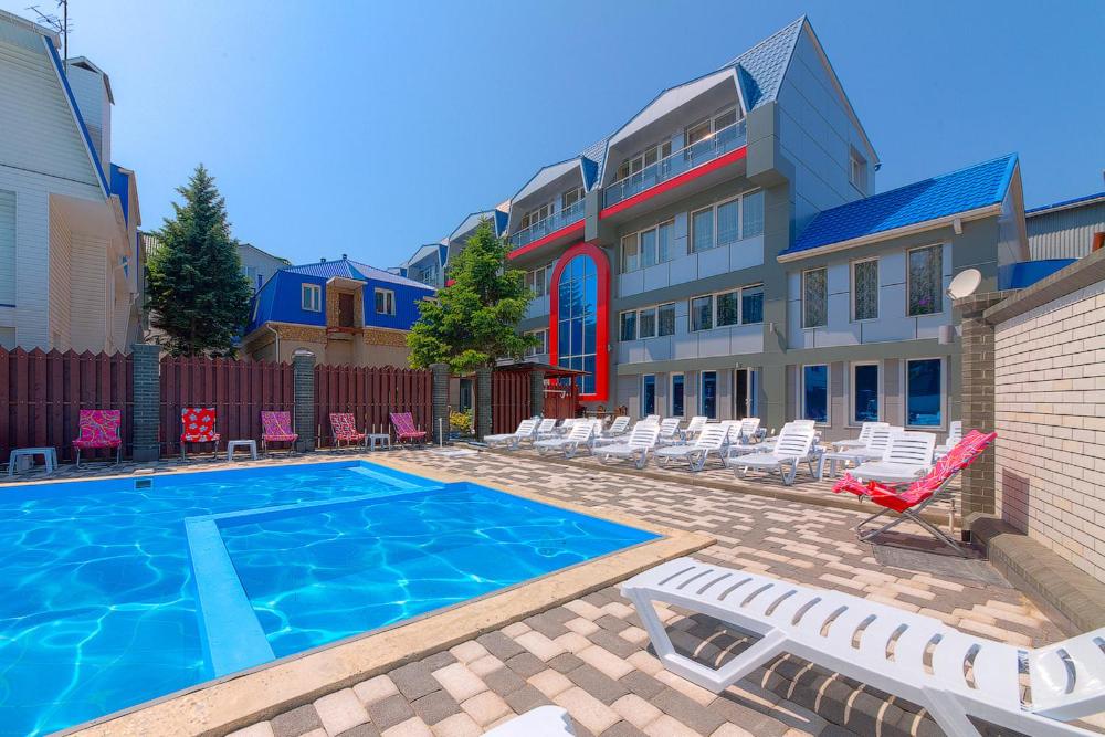 a swimming pool with lounge chairs and a building at Hotel Topol in Anapa