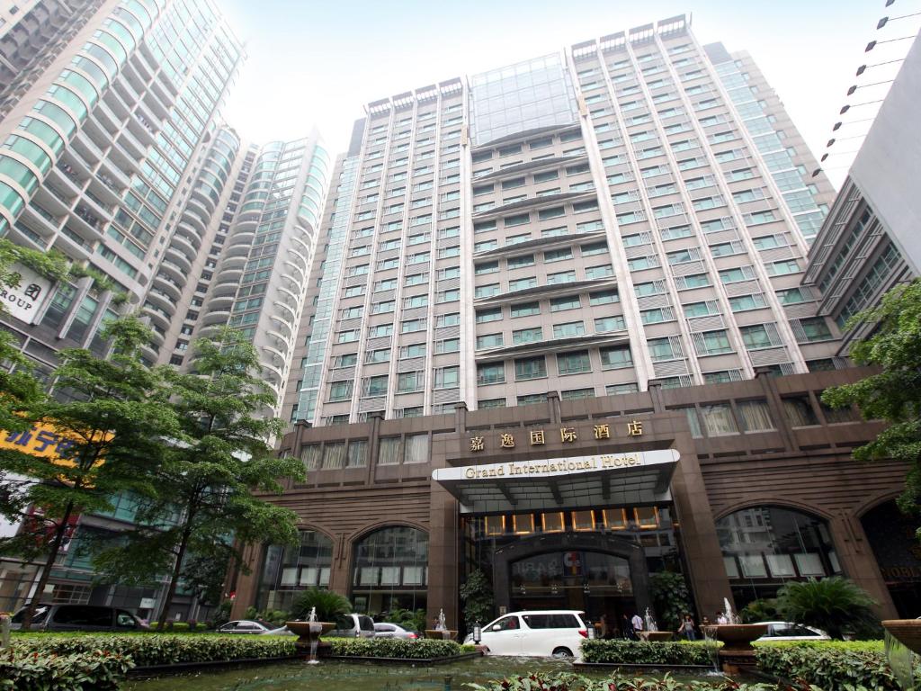 un edificio alto con un coche blanco estacionado frente a él en Grand International Hotel, en Guangzhou