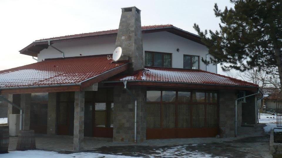 a house with a red roof with snow on it at Вила Дъбовец in Dŭbovets