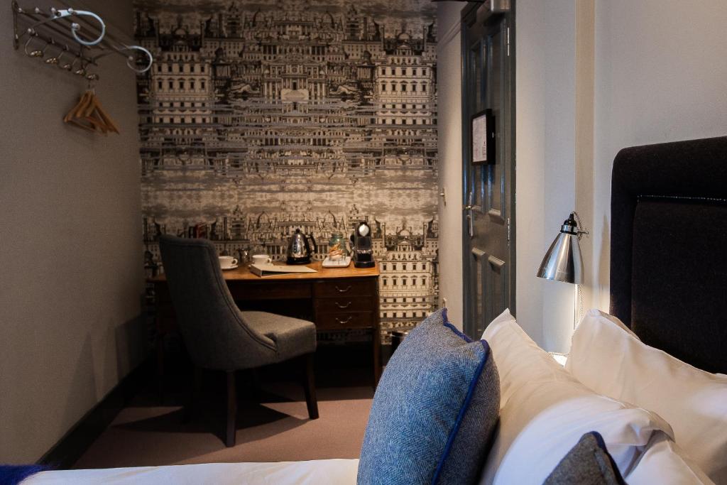 a hotel room with a desk and a bedroom with a bed at Hand & Flower in London