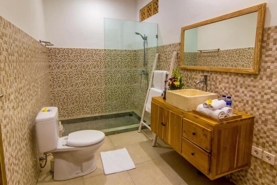 a bathroom with a toilet and a sink and a mirror at Legian Family villa with pool in Legian