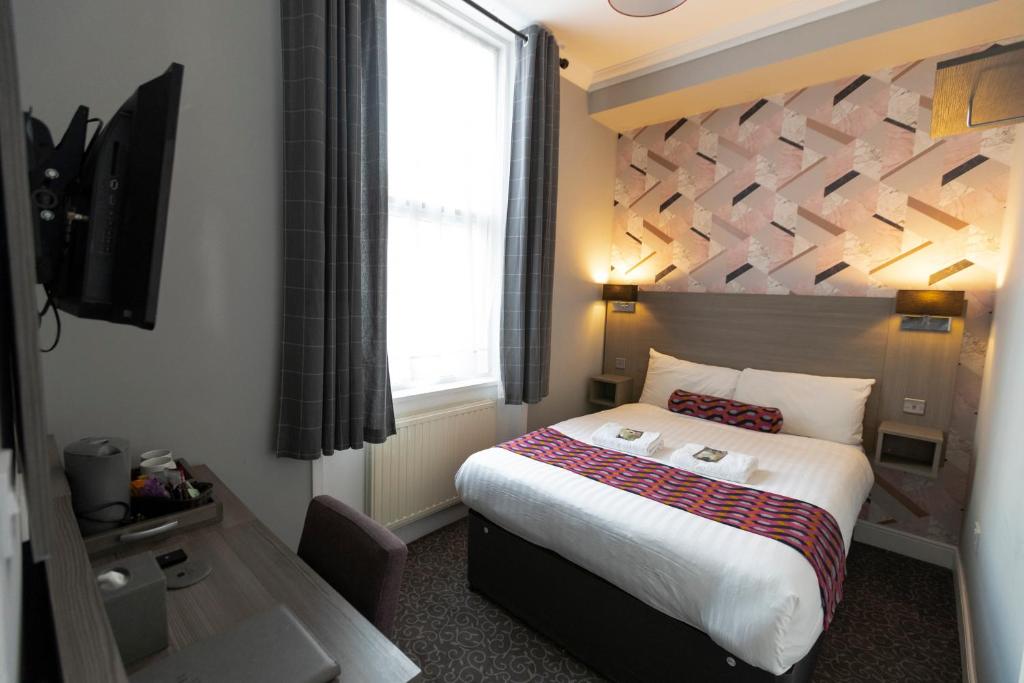 a hotel room with a bed, desk, and lamp at Euro Hotel in London