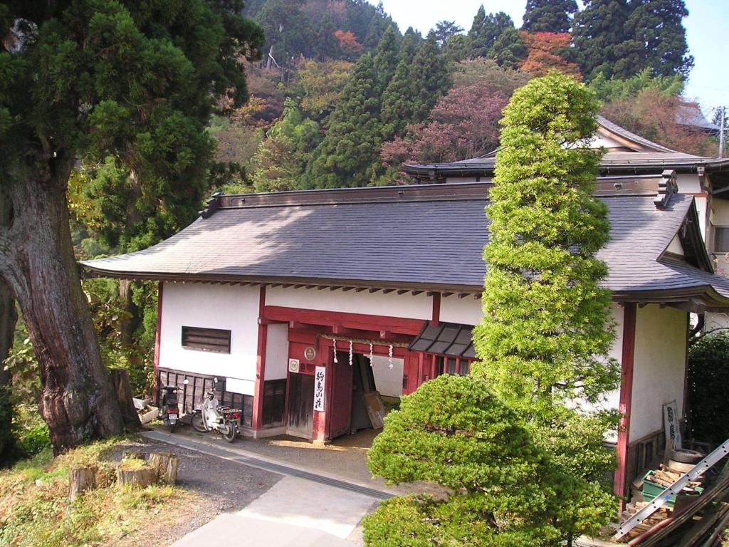 un bâtiment rouge et blanc avec un arbre à côté dans l'établissement Shukubo Komadori-Sanso, à Ome