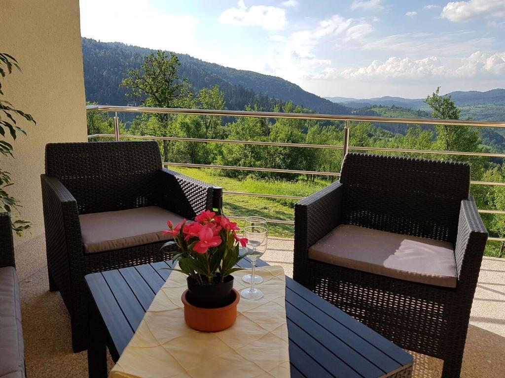 a porch with two chairs and a table with flowers on it at Klementina in Vrbovsko