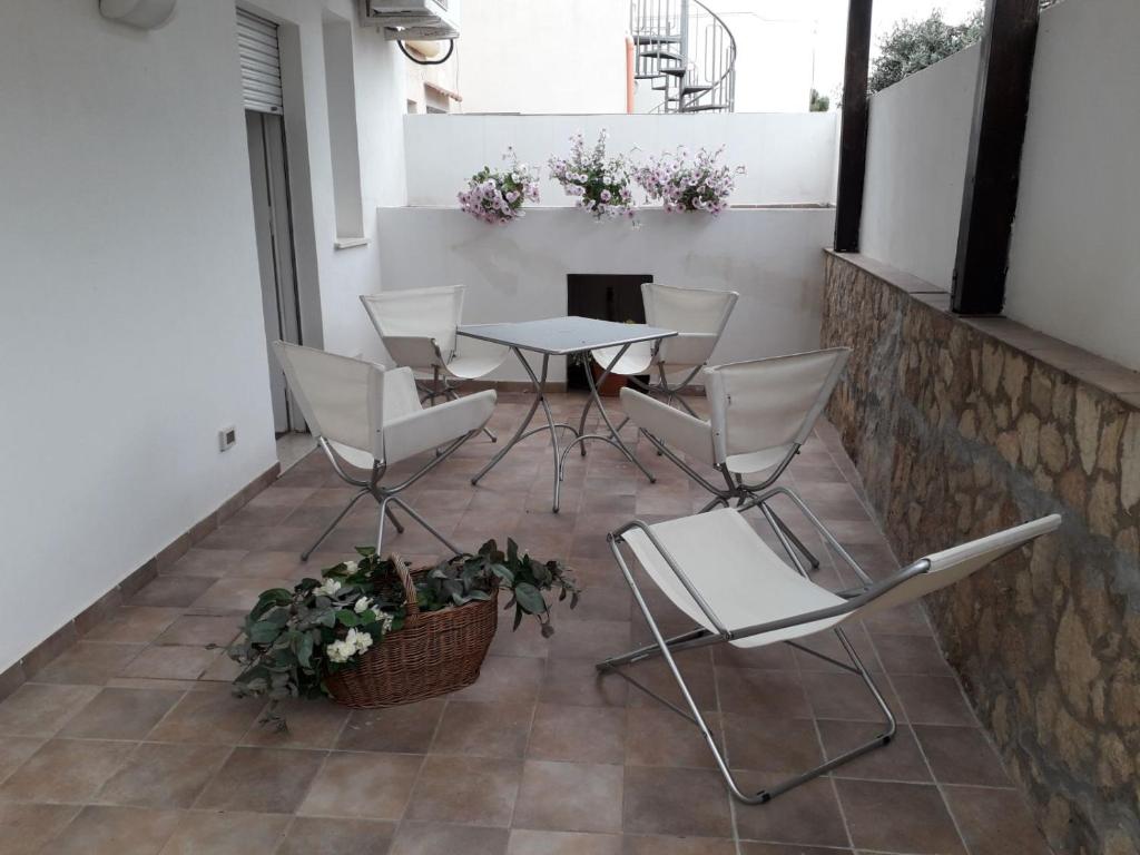 eine Terrasse mit weißen Stühlen, einem Tisch und einer Pflanze in der Unterkunft La Casa Di Roy in Pizzolungo