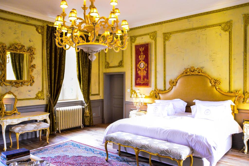 a bedroom with a large bed and a chandelier at Chateau d'Origny, Chambres d'hotes et Restaurant Gastronomique in Ouches