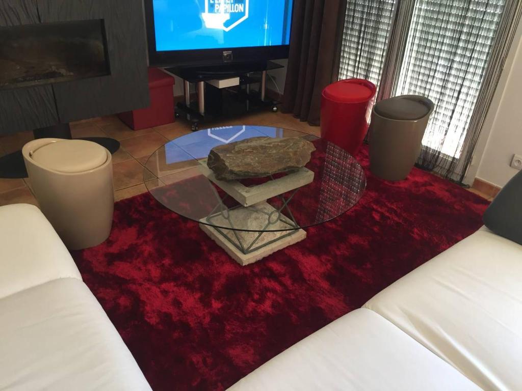 un soggiorno con un tavolo in vetro su un tappeto rosso di Chambre dans une villa a Beaupuy