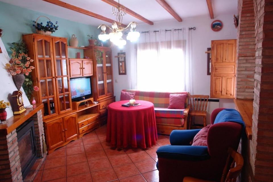sala de estar con sofá, mesa y TV en La Buhardilla, en Arroyo Frío