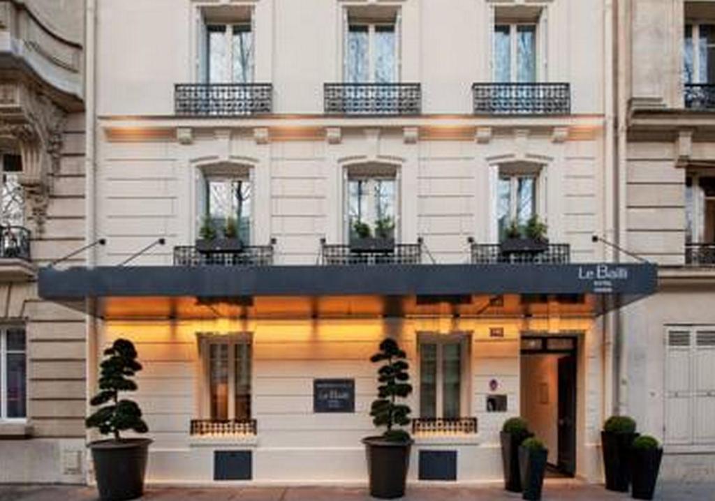 a white building with potted plants in front of it at Le Bailli in Paris