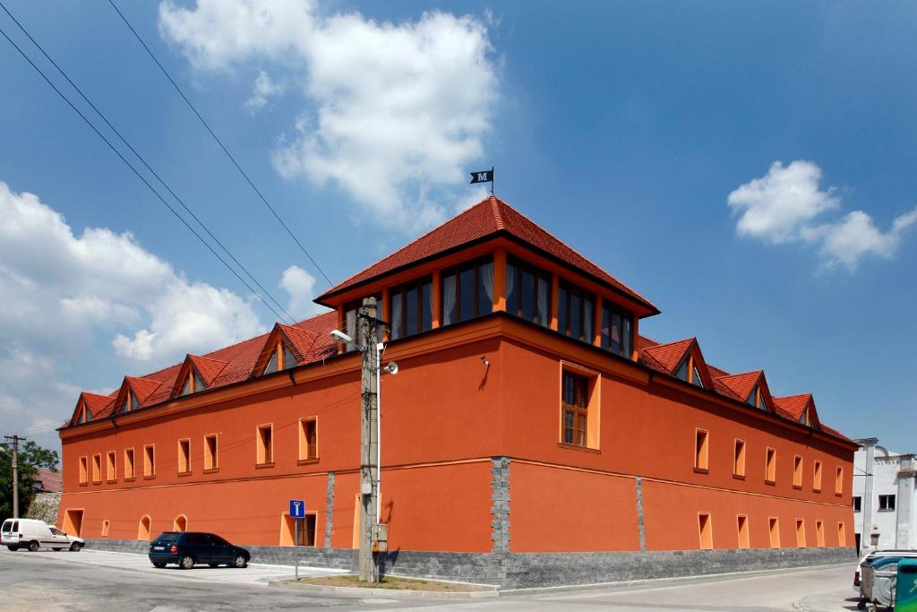 ein großes orangefarbenes Gebäude mit rotem Dach in der Unterkunft Hotel Majolika in Modra