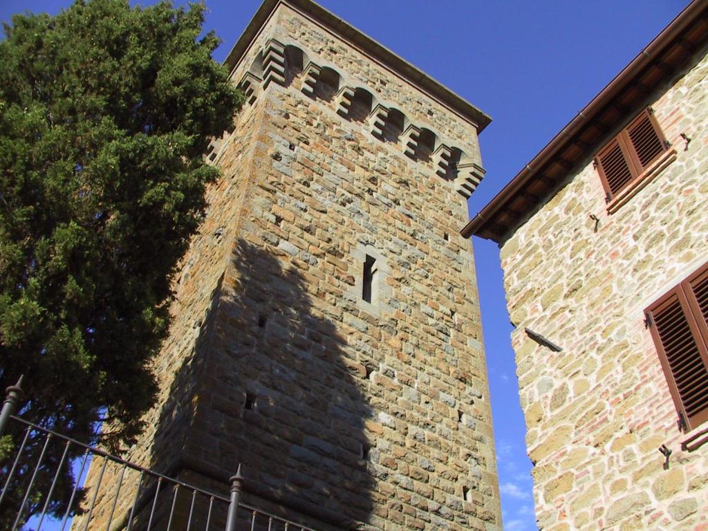 una torre de ladrillo alta con un árbol al lado en Il Colle Rigomagno, en Rigomagno