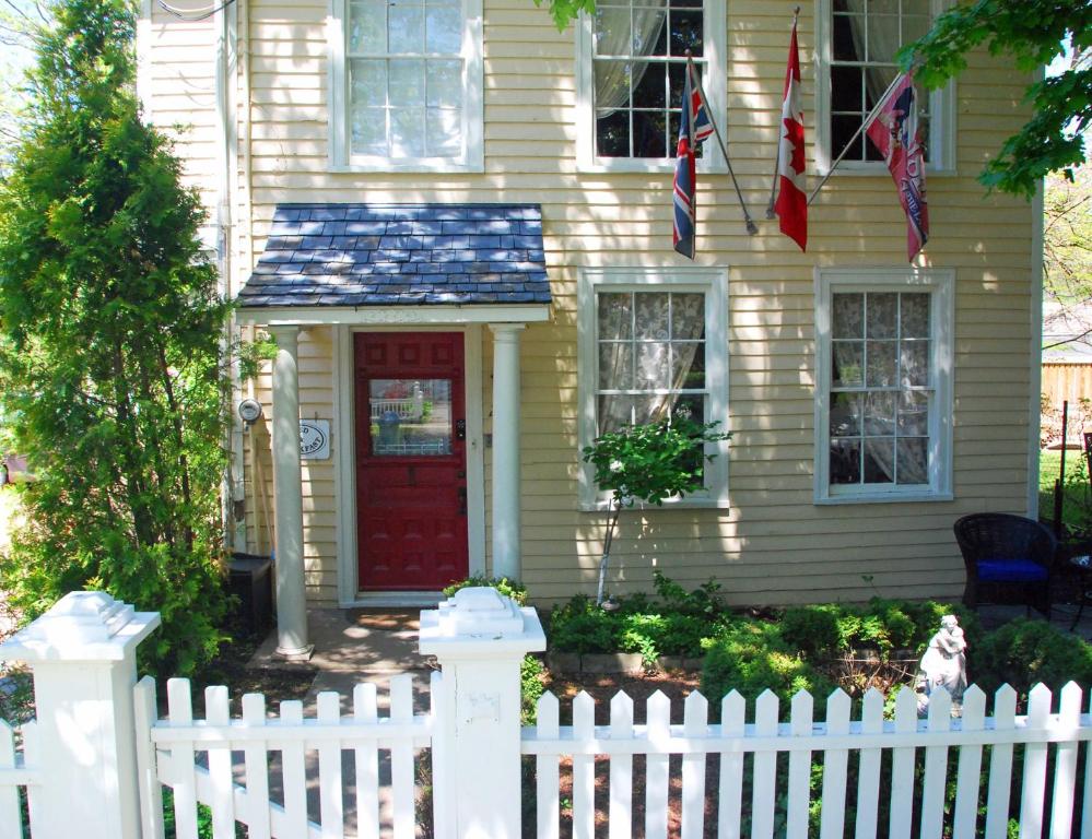 a white fence in front of a house with a red door at Apple Tree Historic B&B in Niagara-on-the-Lake