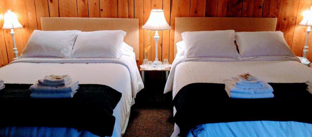 two beds in a hotel room with towels on them at Pine Hill Arms Hotel in Pine Hill