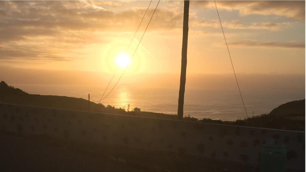 um pôr-do-sol sobre o oceano com o sol no céu em Fajazinha Cottage em Faja Grande