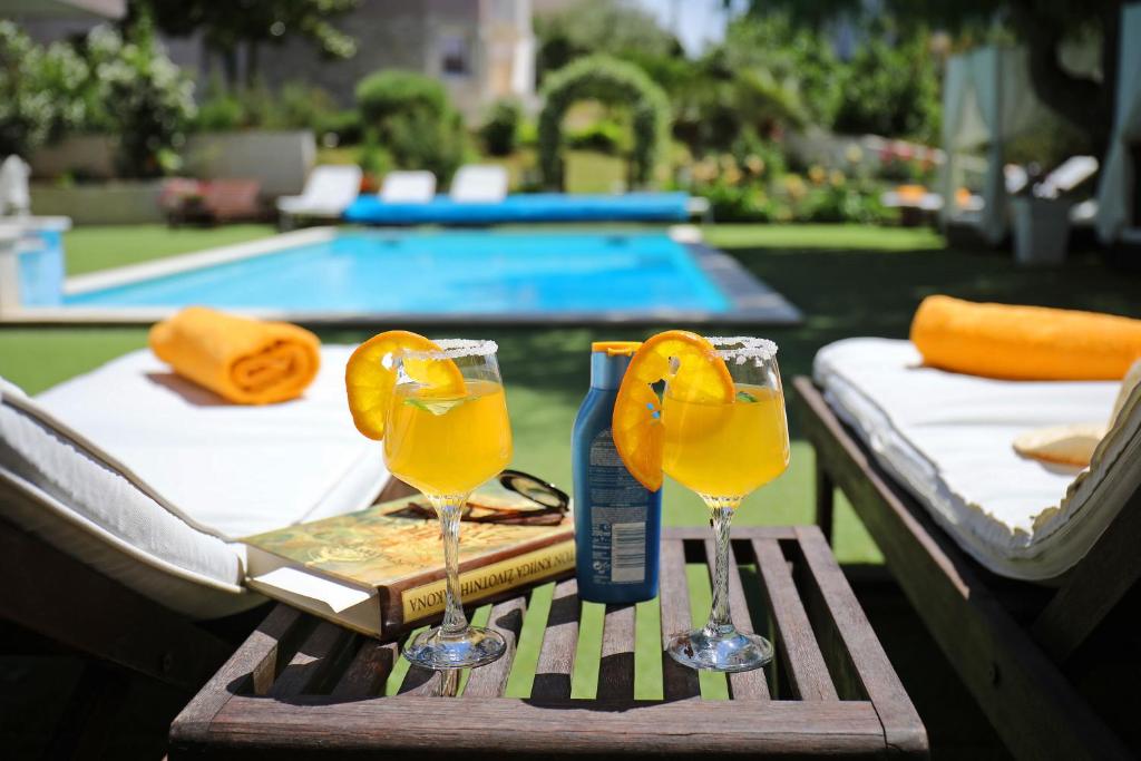 dois copos de sumo de laranja numa mesa perto de uma piscina em Apartments Mirakul em Zadar