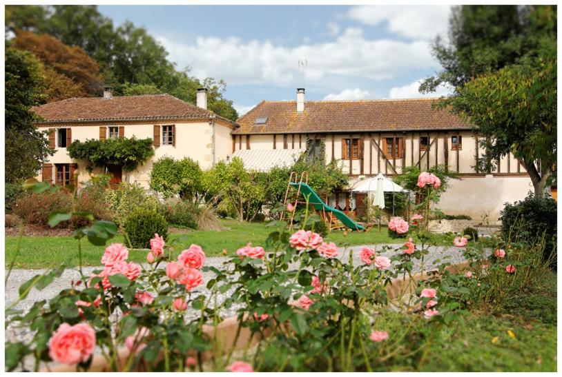 uma casa com um jardim com rosas em frente em La Ferme des Grisettes em Montesquiou