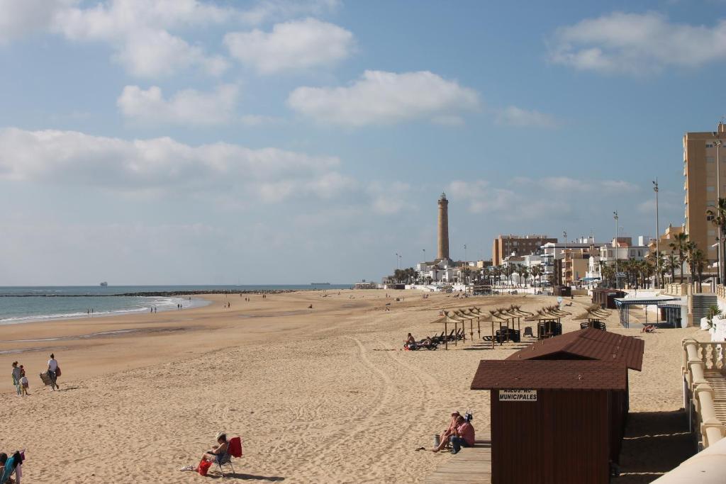 a beach with people on the sand and the ocean at Chipiona CERCA DE LA PLAYA in Chipiona