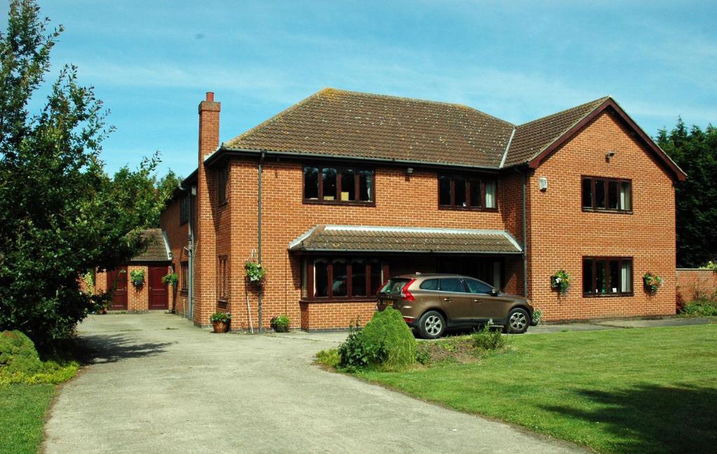 a brick house with a car parked in the driveway at The Farmhouse B&B in Goole