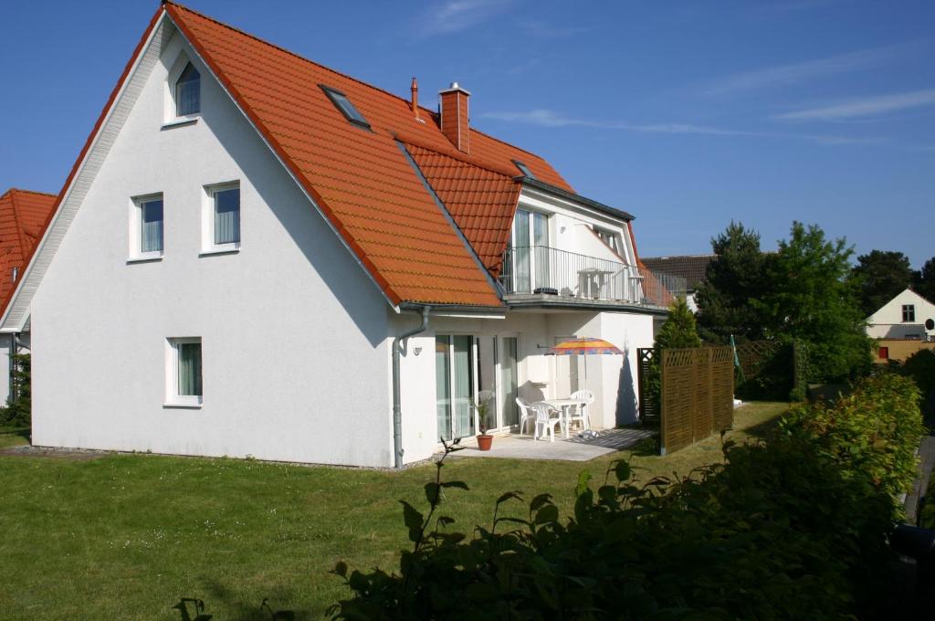 a white house with an orange roof at Haus Galerie 1. OG in Ostseebad Karlshagen