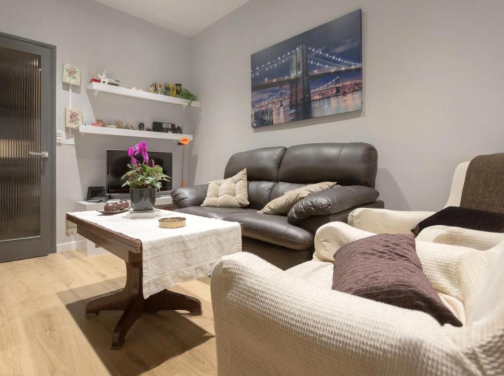 a living room with a leather couch and a table at Apartamento Céntrico in Ripoll