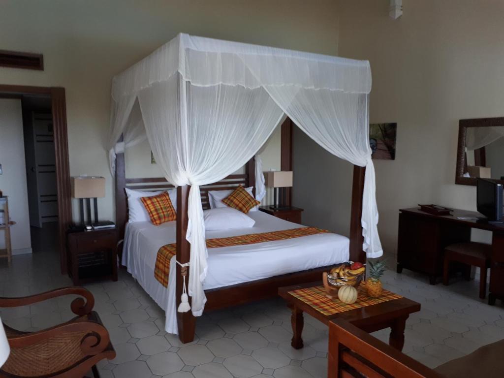 a bedroom with a large bed with a canopy at Appartement à la Résidence LA PLANTATION RESORT and SPA in Saint-François