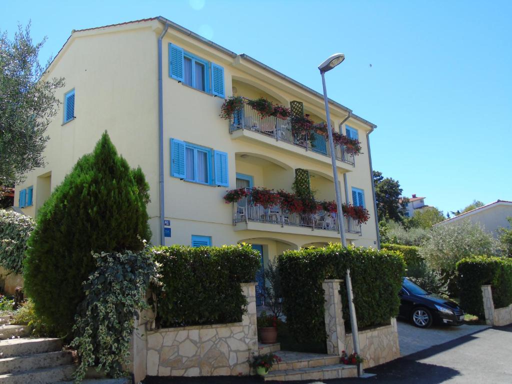 un edificio blanco con ventanas y arbustos azules en Apartment Karla, en Poreč