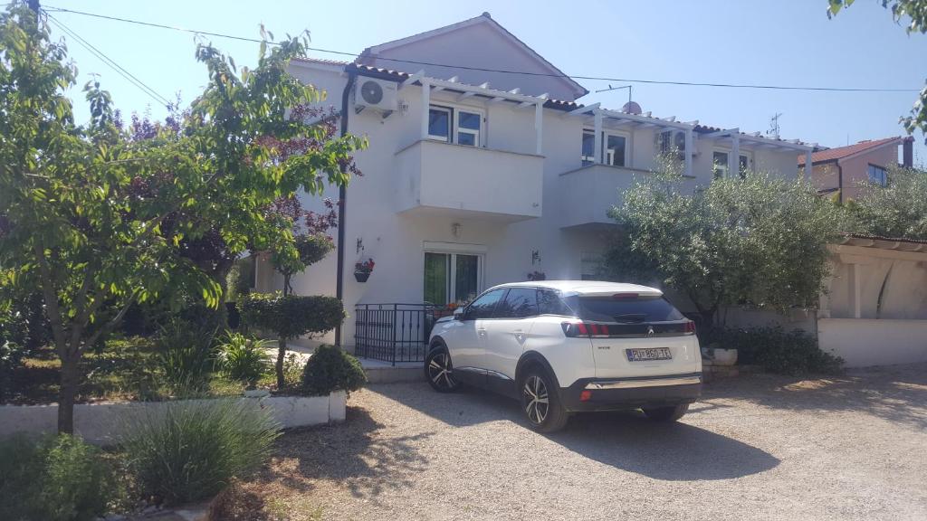 un coche blanco estacionado frente a una casa en Martina Guest house, en Poreč