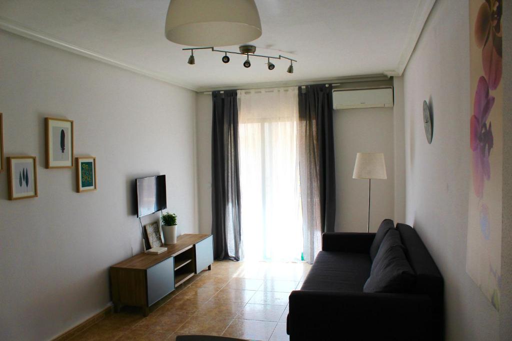sala de estar con sofá y ventana en Katy Apartments, en Playas de Orihuela