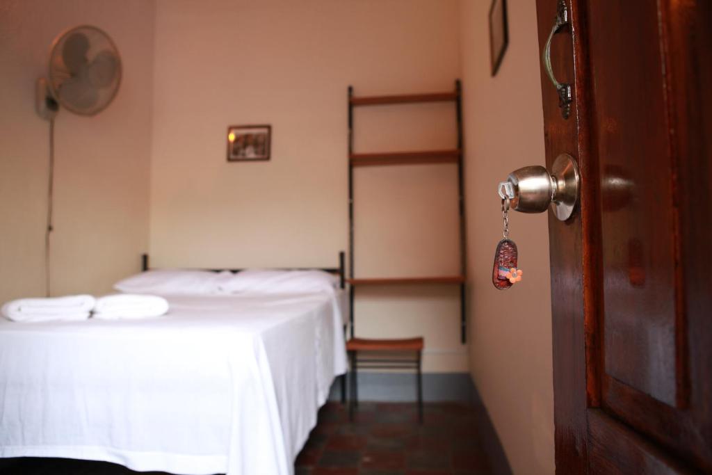 a room with two beds with white sheets and a door at Hostal La Tortuga Booluda in León