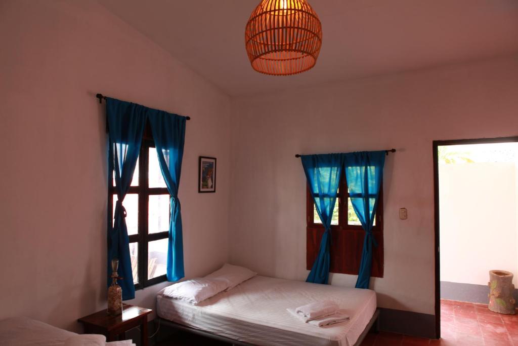 a bedroom with two beds and blue curtains and a chandelier at Hostal La Tortuga Booluda in León