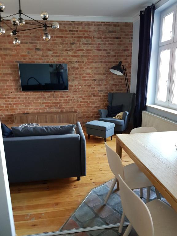 a living room with a couch and a brick wall at Lawendowa 2-3 Gdańsk in Gdańsk
