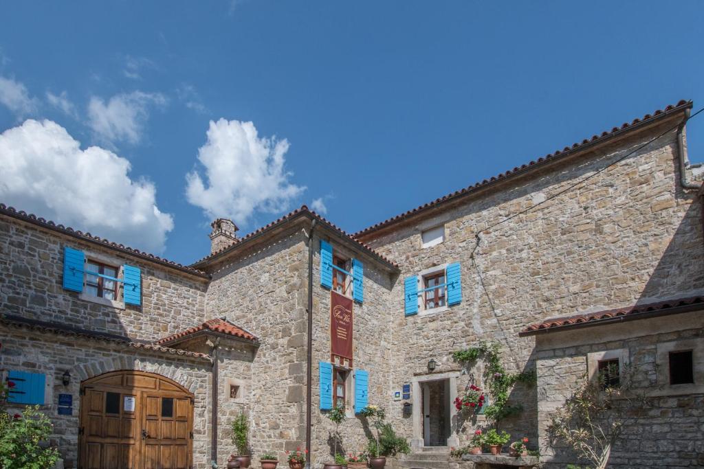 un gran edificio de piedra con ventanas azules y puerta de madera. en Apartments Villa San Vito en Grožnjan