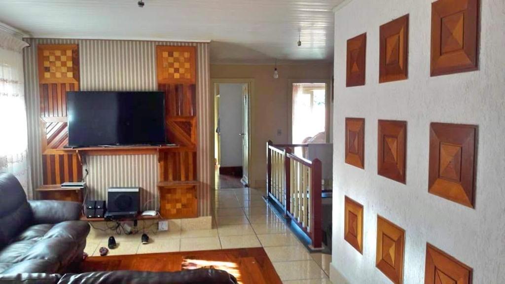 a living room with a couch and a flat screen tv at Recanto do Sossego in Campos do Jordão