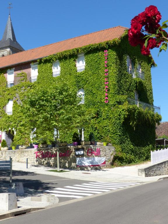 un bâtiment recouvert de lierre avec des fleurs rouges sur lui dans l'établissement Hôtel du Château, à Alvignac