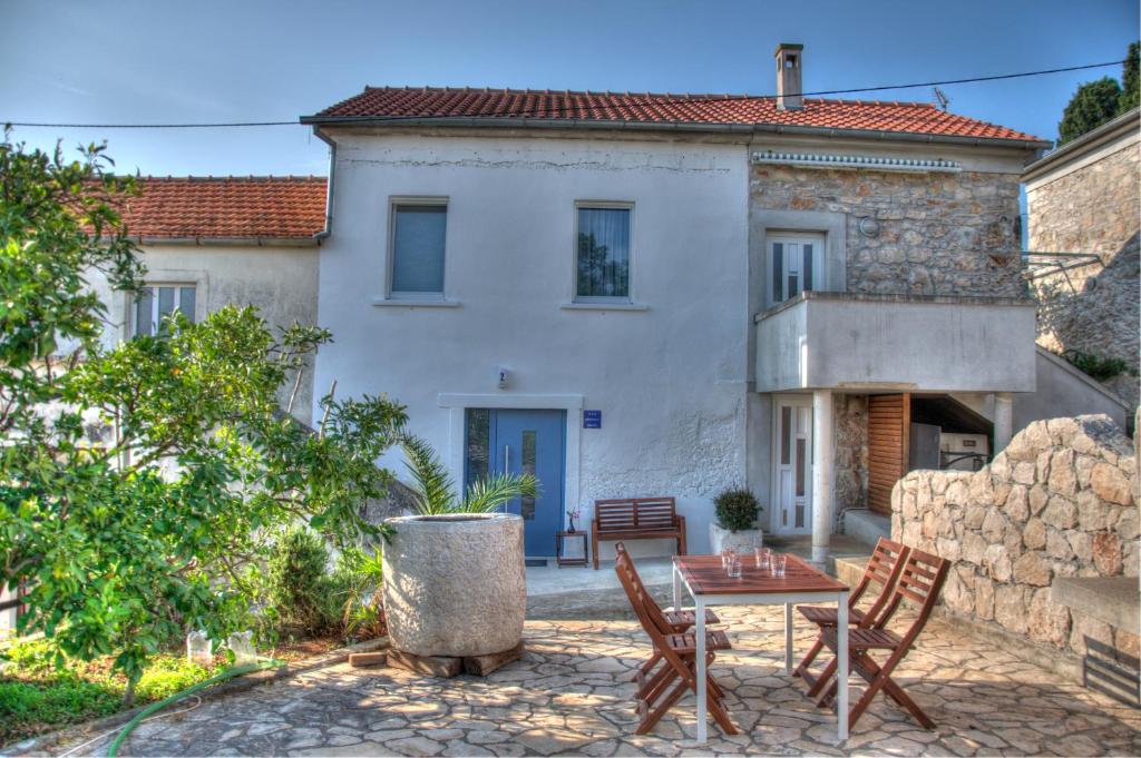 a patio with a table and chairs in front of a house at Apartmani Harmonija in Žman