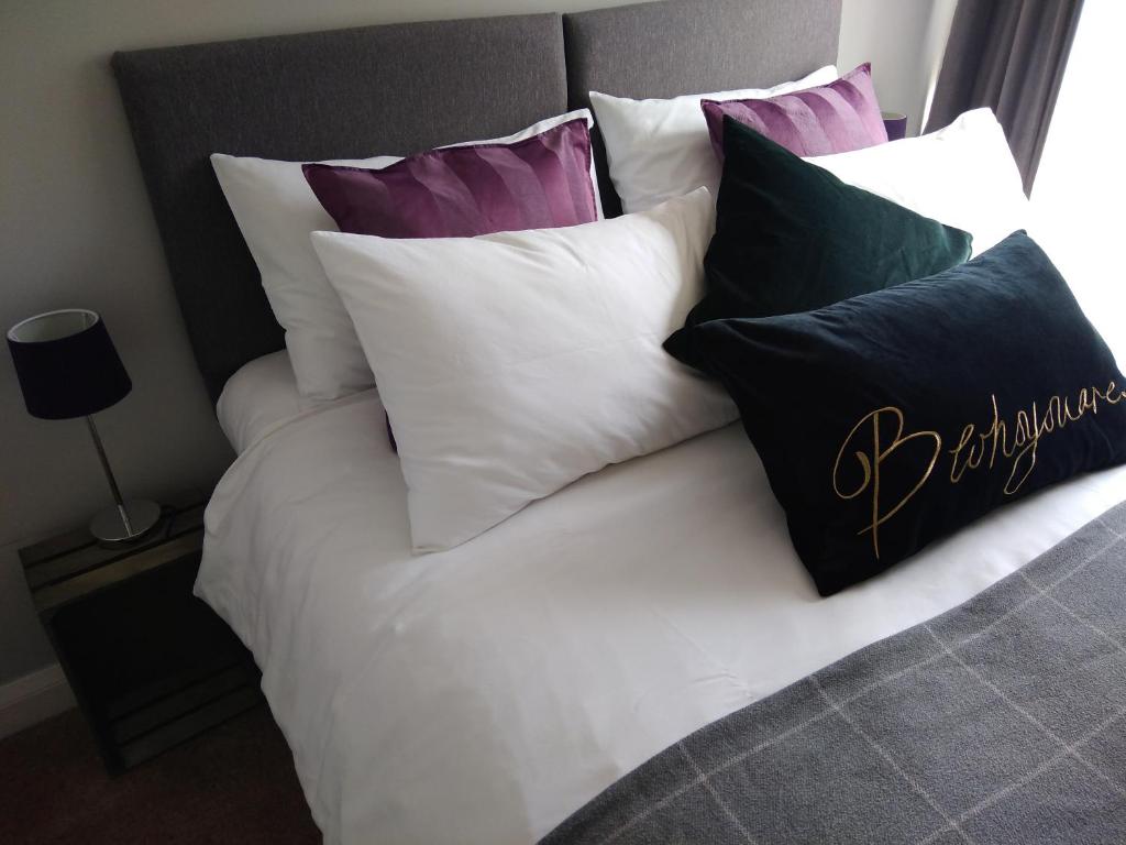 a bed with a bunch of pillows on it at Sleep, Eat, Repeat Bed and Breakfast in Macclesfield
