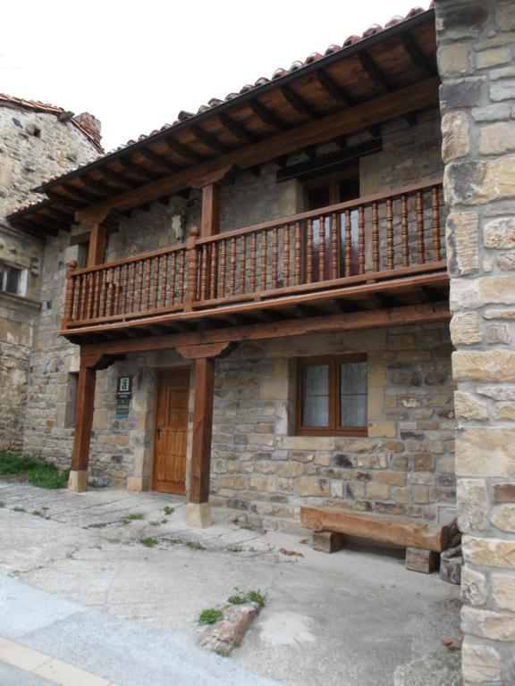 un edificio de piedra con balcón de madera y banco en Casa La Abuela, en San Mamés