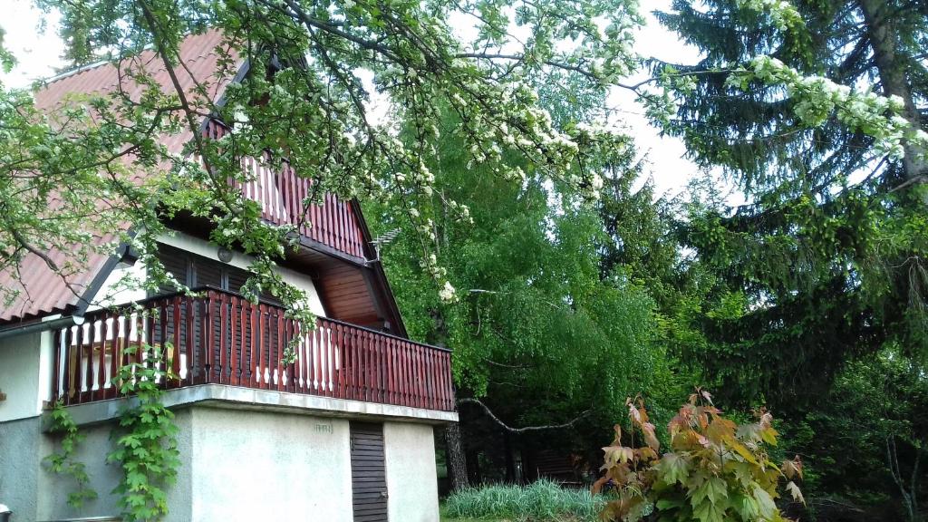 a house with a red balcony and some trees at Holiday house Nature in Ravna Gora