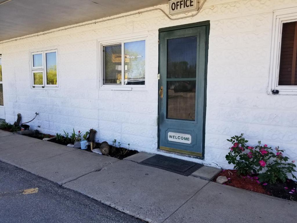 a white house with a green door on the side of it at Melsask Motel in Melville
