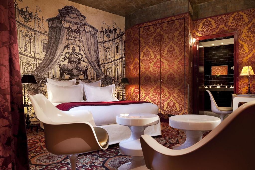 a bedroom with a bed and a couch and chairs at Hotel du Petit Moulin in Paris