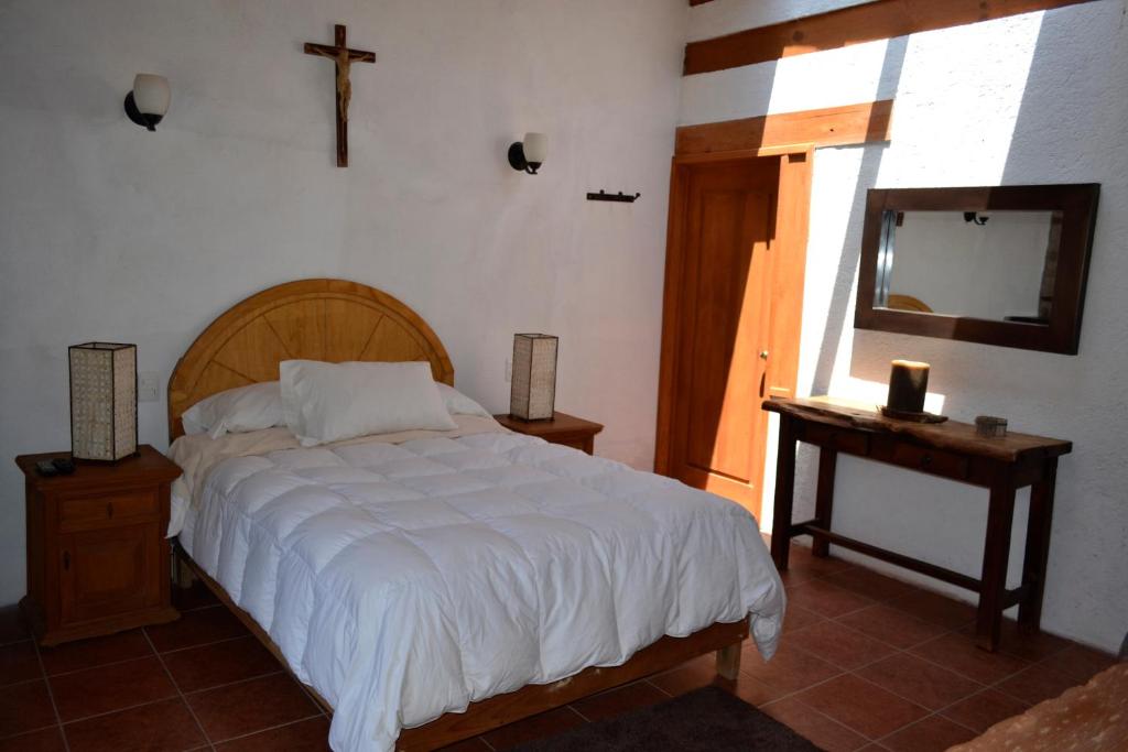 1 dormitorio con 1 cama y 1 cruz en la pared en Hotel Boutique El Campirano en Amanalco de Becerra