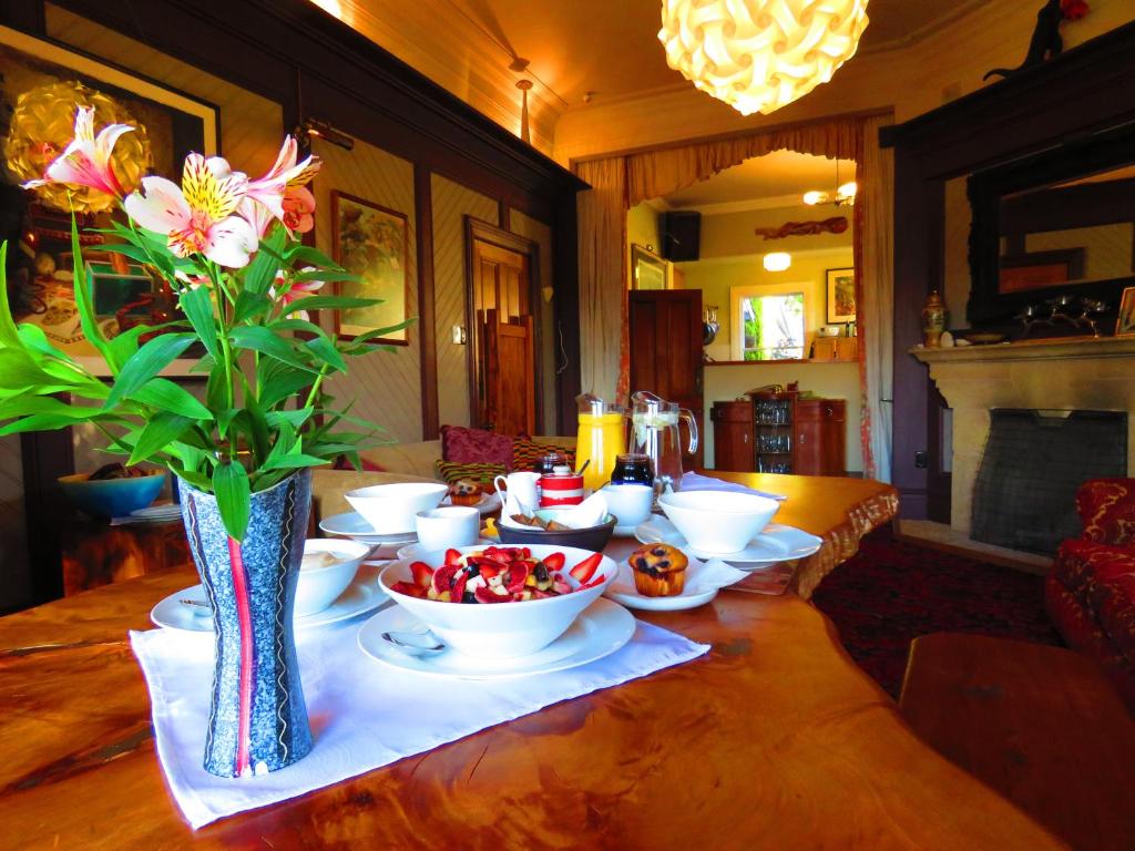 a table with bowls of fruit and a vase with flowers at Shady Rest Bed & Breakfast in Takaka
